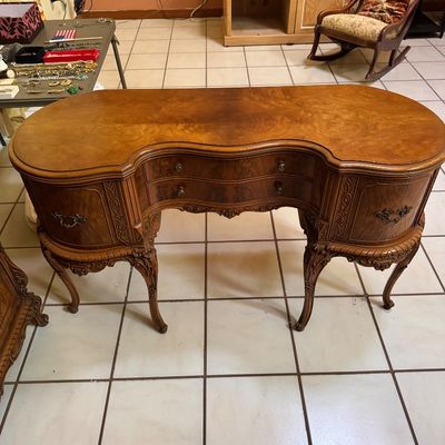 Vintage French Provincial style kidney-shaped vanity desk featuring ornate carved wood details, cabriole legs, and a rich burl wood finish.
