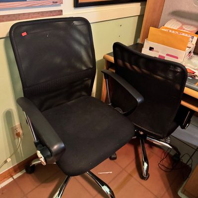 Pair of modern black mesh office chairs with adjustable armrests and chrome-finished rolling bases.
