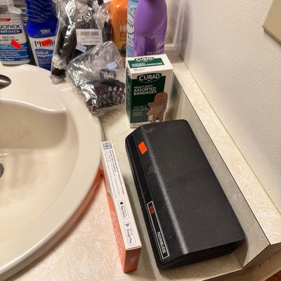 Vintage Norelco electric shaver in its black plastic hard case, displayed alongside various personal care items and toiletries on a...