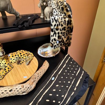 Assorted safari-themed decor items, including elephant figurines, a ceramic leopard, a faux leopard print scarf, and a piece of cholla...
