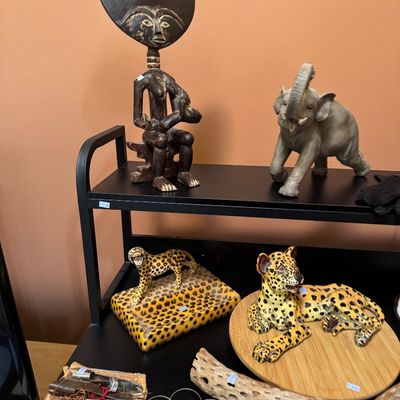 Assorted decorative items on black shelving, including an African Ashanti Akua'ba fertility doll, an elephant figurine, and two...
