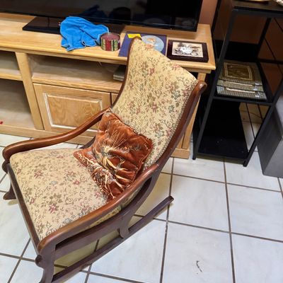 Vintage wooden rocking chair with floral tapestry upholstery and a decorative velvet accent pillow.
