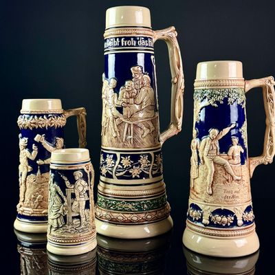A Set of Four German Salt-Glazed Relief-Molded Stoneware Beer Steins