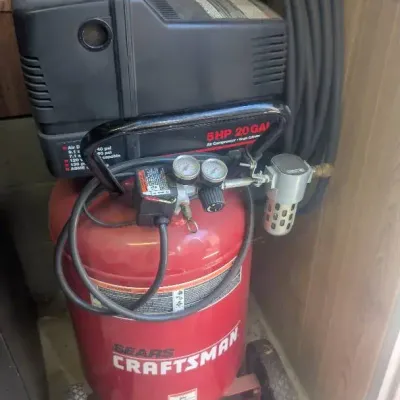 Red Craftsman 5 HP 20-Gallon Vertical Air Compressor with Black Motor Housing and a Coiled Hose