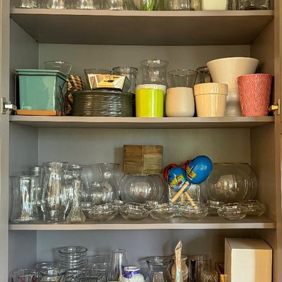 Cabinet filled with glassware vases candle holders planters and decorative vessels available at a Bellevue Estate Sale. The collection...