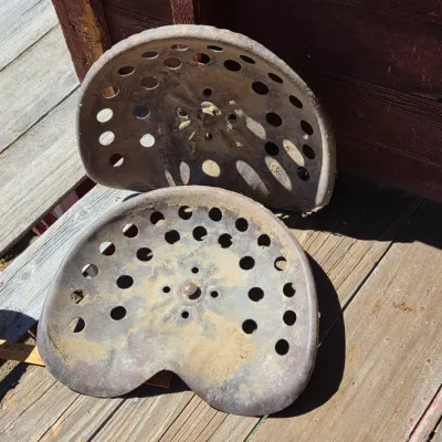 Two vintage steel tractor seats