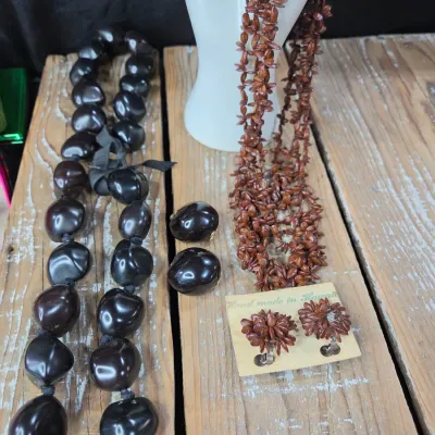 Polished black kukui nut beads paired with matching clip-on earrings, and a Hawaiian seed pod lei and matching earrings