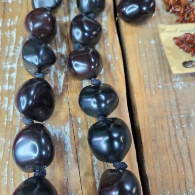 Polished black kukui nut beads paired with matching clip-on earrings, and a Hawaiian seed pod lei and matching earrings