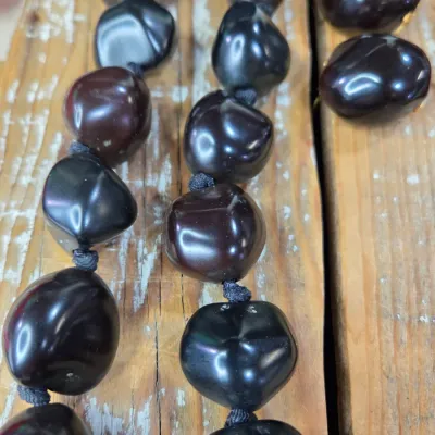 Polished black kukui nut beads paired with matching clip-on earrings, and a Hawaiian seed pod lei and matching earrings