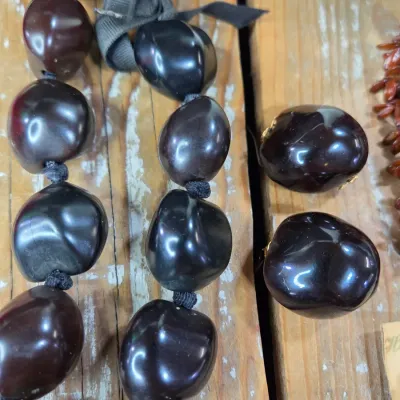 Polished black kukui nut beads paired with matching clip-on earrings, and a Hawaiian seed pod lei and matching earrings
