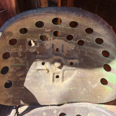 Two vintage steel tractor seats - one partially green