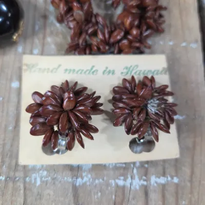 Polished black kukui nut beads paired with matching clip-on earrings, and a Hawaiian seed pod lei and matching earrings