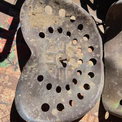Two vintage steel tractor seats - one partially green