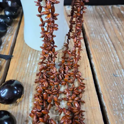 Polished black kukui nut beads paired with matching clip-on earrings, and a Hawaiian seed pod lei and matching earrings
