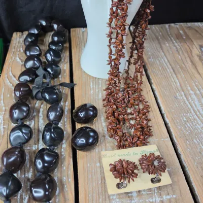 Polished black kukui nut beads paired with matching clip-on earrings, and a Hawaiian seed pod lei and matching earrings