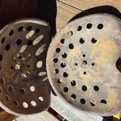 Two vintage steel tractor seats