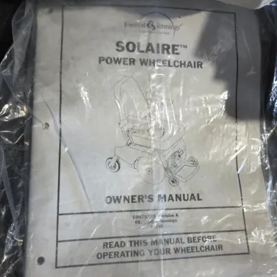 Older Solaire motorized power wheelchair with owner's manual and accessories