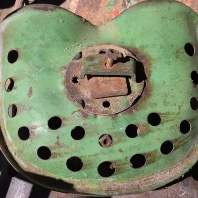 Two vintage steel tractor seats - one partially green