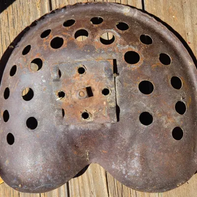 Two vintage steel tractor seats