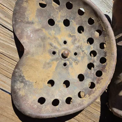 Two vintage steel tractor seats