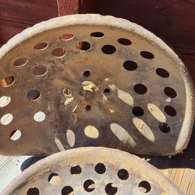 Two vintage steel tractor seats