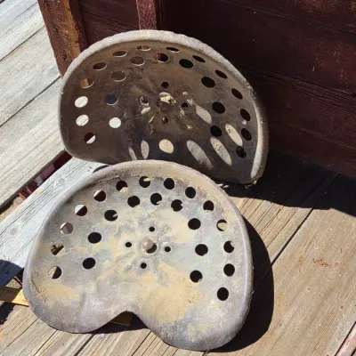 Two vintage steel tractor seats
