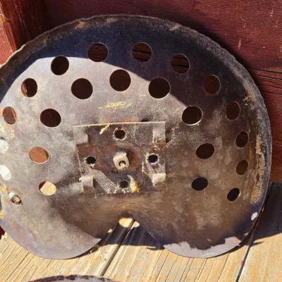 Two vintage steel tractor seats