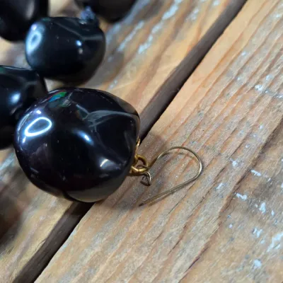 Polished black kukui nut beads paired with matching clip-on earrings, and a Hawaiian seed pod lei and matching earrings