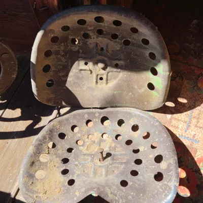 Two vintage steel tractor seats - one partially green