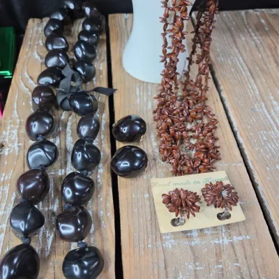 Polished black kukui nut beads paired with matching clip-on earrings, and a Hawaiian seed pod lei and matching earrings