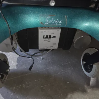 Older Solaire motorized power wheelchair with owner's manual and accessories