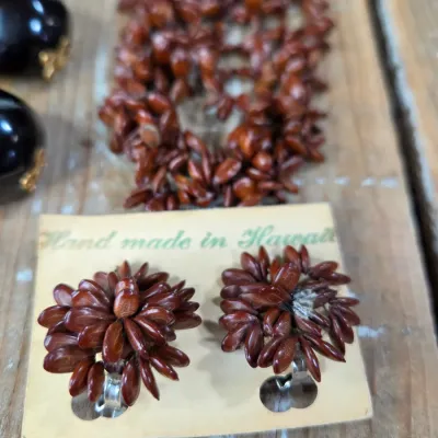 Polished black kukui nut beads paired with matching clip-on earrings, and a Hawaiian seed pod lei and matching earrings