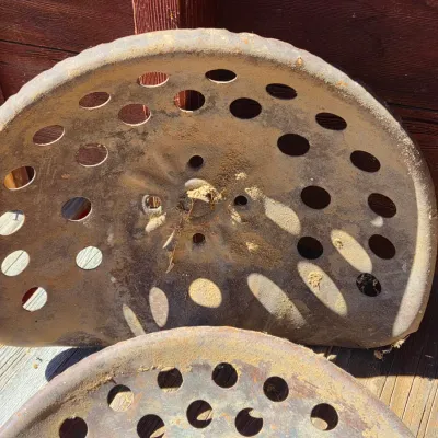 Two vintage steel tractor seats
