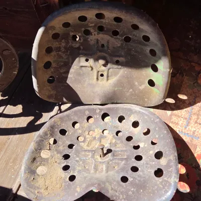 Two vintage steel tractor seats - one partially green