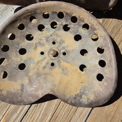 Two vintage steel tractor seats