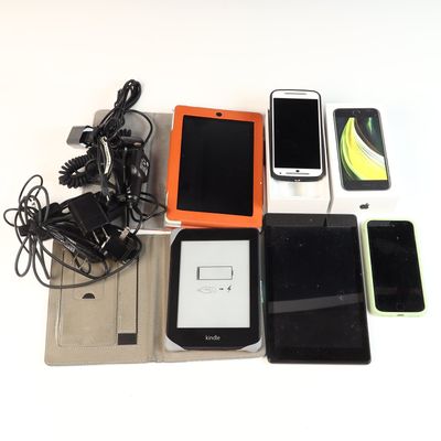 An Assortment of Portable Electronic Devices including a Kindle E-Reader, Tablets, Smartphones, Apple Retail Packaging, and Charging...