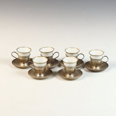 A Set of Sterling Silver and Porcelain Demitasse Cups and Saucers