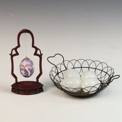 A real Egg on Wooden Stand and a Collection of White Handblown Glass Eggs in a Wire Basket