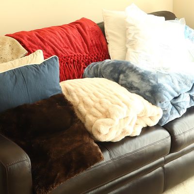 An Assortment of Five Throw Blankets, Four Pillows, and a Three Seat Leather Sofa