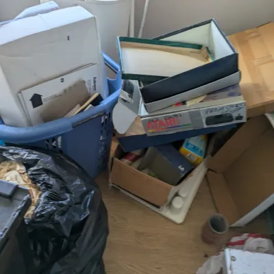 Sale Photo Thumbnail #118: Vintage Atari Video Computer System box containing miscellaneous items, surrounded by storage bins, cardboard boxes, and household clutter.