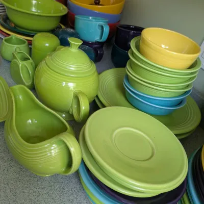 Sale Photo Thumbnail #124: Assorted vintage Fiesta dinnerware in various colors, including a lime green teapot, gravy boat, bowls, and plates.