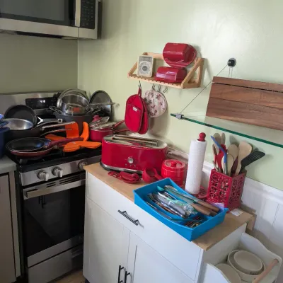 Sale Photo Thumbnail #123: Kitchen cart with wood top and white cabinets, featuring a red toaster, utensils, and various kitchenware items.