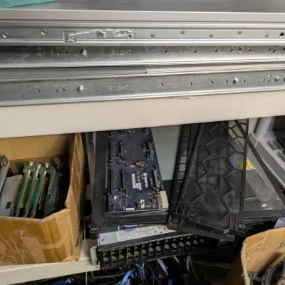 Sale Photo Thumbnail #111: Assorted vintage computer hardware and server components, including rack rails, circuit boards, and server chassis parts.