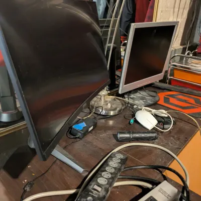 Sale Photo Thumbnail #105: MSI curved computer monitor and a smaller silver-bezel secondary monitor, shown on a desk with power strips, a mouse, and a desk lamp.