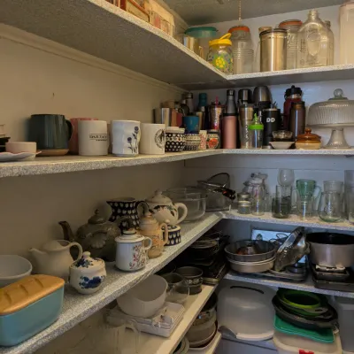 Sale Photo Thumbnail #121: Pantry shelves stocked with various kitchenware, including ceramic mugs, teapots, glassware, mixing bowls, and storage containers.