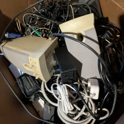 Sale Photo Thumbnail #104: Cardboard box filled with vintage computer speakers, power adapters, and various tangled cables.