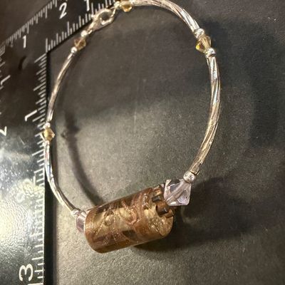artisan silver-tone wire bracelet featuring a prominent cylindrical champagne and amber foil glass focal bead flanked by pale pink bicone...
