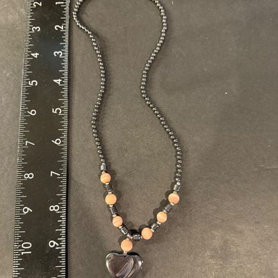 Vintage beaded necklace featuring metallic gray hematite beads and peach cat's-eye glass beads accented with a heart-shaped pendant.