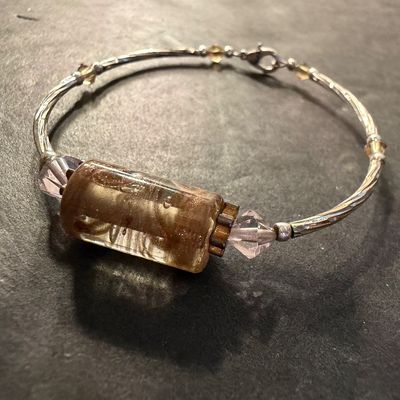 artisan silver-tone wire bracelet featuring a prominent cylindrical champagne and amber foil glass focal bead flanked by pale pink bicone...