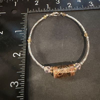 artisan silver-tone wire bracelet featuring a prominent cylindrical champagne and amber foil glass focal bead flanked by pale pink bicone...